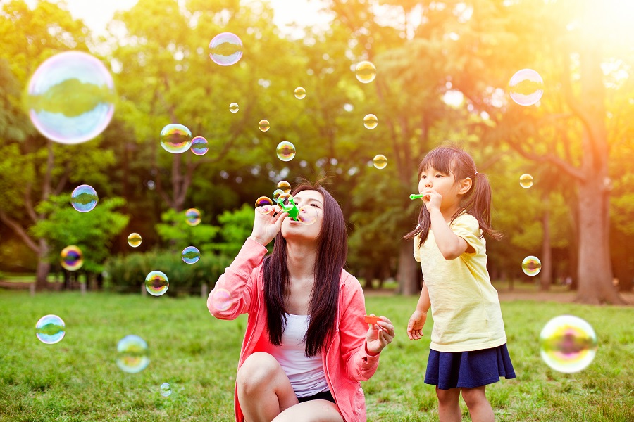 Mother and daughter having fun in park with Soap Bubbles